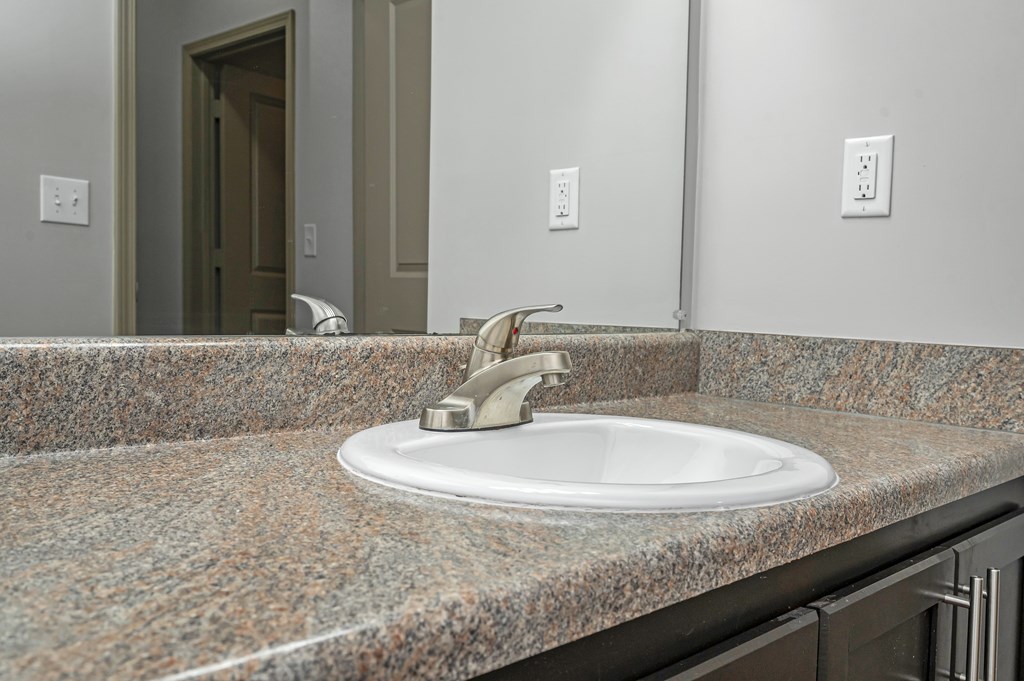 A bathroom sink with a granite counter top.